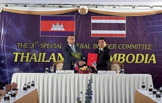 Tea Seiha (I) y Natthaphon Narkphanit (D), los ministros de Defensa de Camboya y Tailandia, respectivamente, intercambian el acuerdo firmado de cese al fuego. Foto: EFE