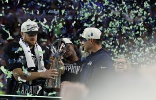 El entrenador en jefe de los Seattle Seahawks, Mike Macdonald (der.), entrega el Trofeo Lombardi al mariscal de campo, Sam Darnold. Foto: EFE