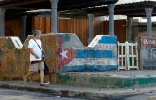 Un hombre camina junto a una pintura de la bandera cubana en La Habana (Cuba). Foto: EFE