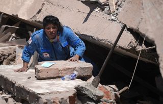 Una integrante de la Cruz Roja de Colombia busca entre los escombros de una edificación colapsada. Foto: EFE