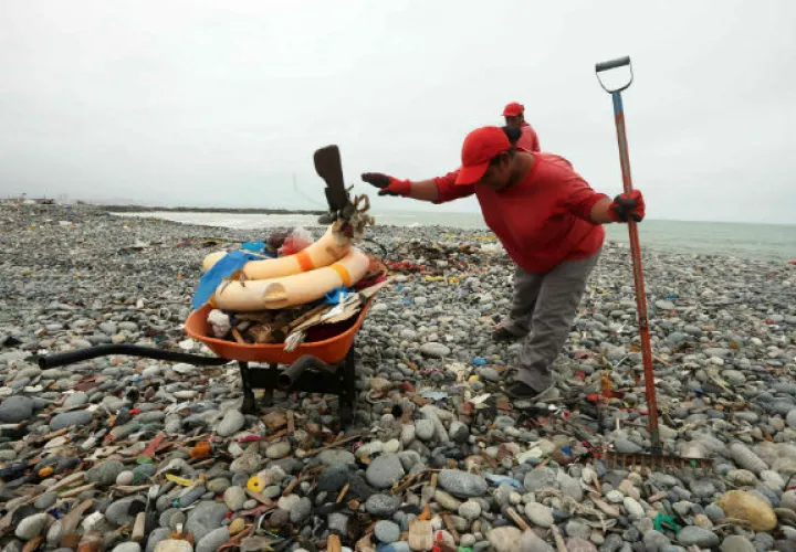 Una trabajadora de limpieza recoge restos plásticos y otros materiales. Foto/ EFE