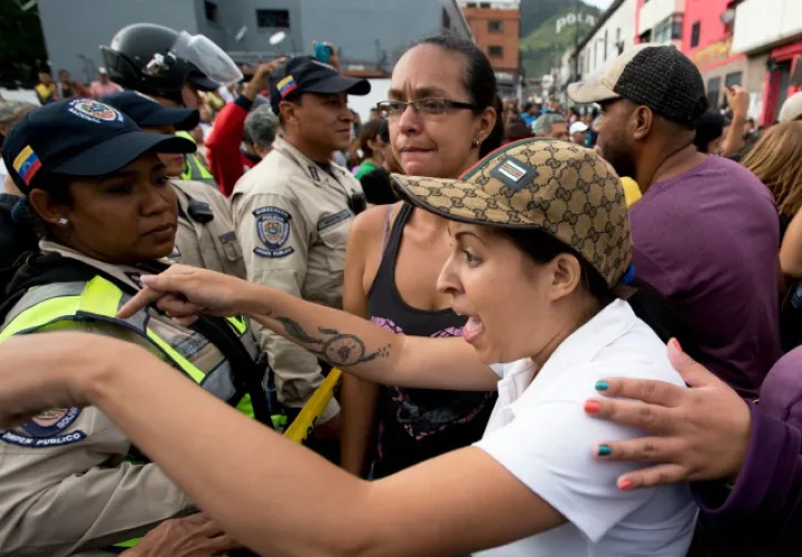 Una mujer reclama a un policía por no permitirle avanzar en su protesta exigiendo comida. /Foto AP
