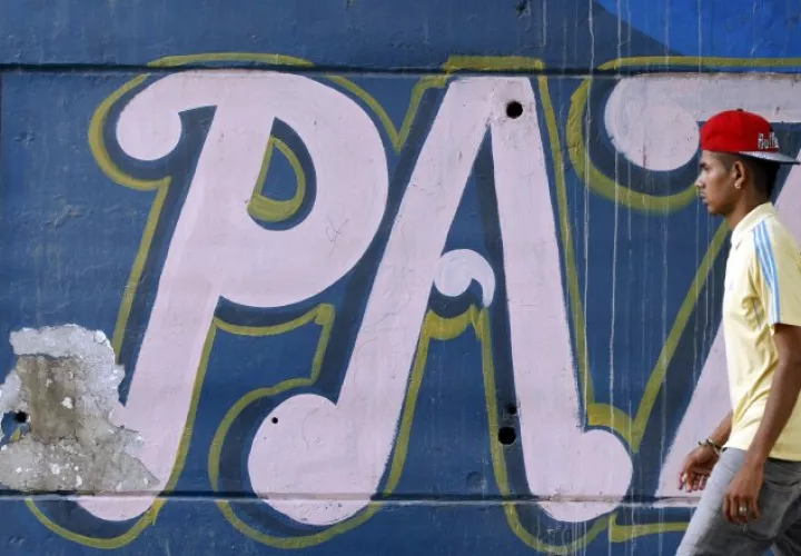 Un hombre camina frente a un mural alusivo a la paz en Cali. /Foto EFE
