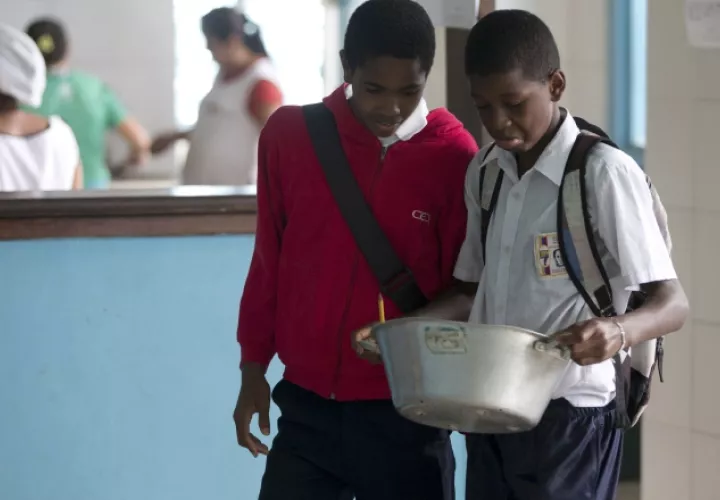 Jóvenes  estudiantes reciben algo de comida. /Foto AP
