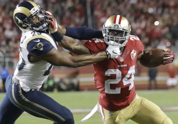 Shaun Draughn (24), de los 49ers trata de sacarse la marca de T.J. McDonald (25). / Foto AP 