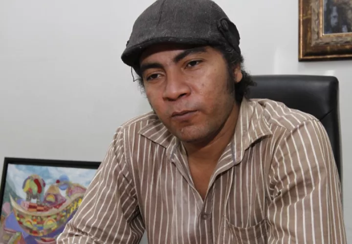 Radamés Pinzón, artista plástico oriundo de Penonomé y uno de sus cuadros de la ciudad imaginaria. /Foto Edward Santos.