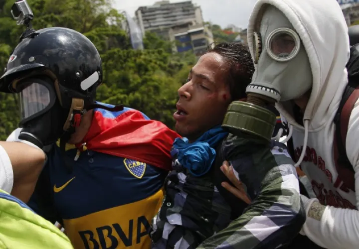 Un manifestante herido es cargado por otros estudiantes durante las protestas de ayer en Caracas. /Foto AP