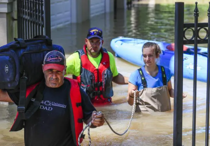 Residentes de Houston, Texas, jalan un bote con remos para transportarse a un lugar seguro. /Foto EFE.