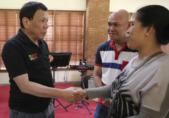Rodrigo Duterte junto a los padres de joven muerto. Foto/ EFE