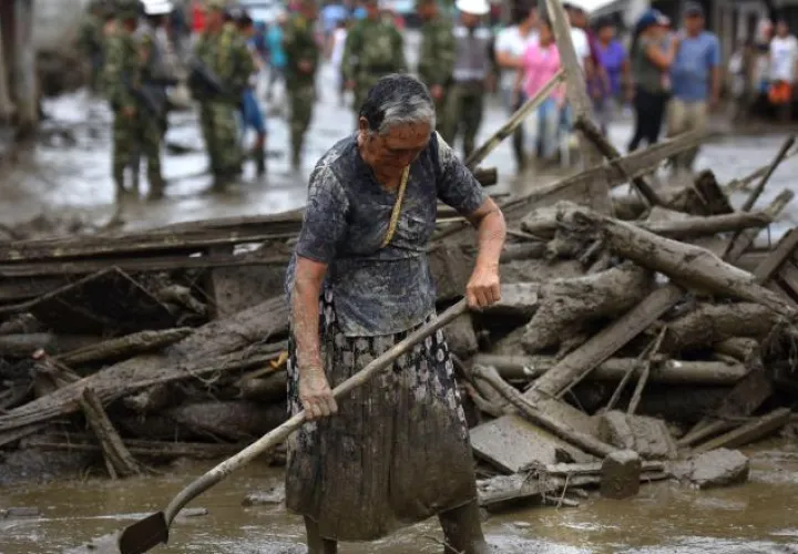 Una mujer limpia la calle de lodo en el municipio de Corinto. /Foto EFE
