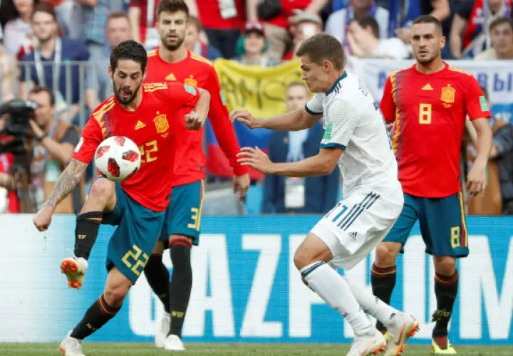 El centrocampista español Isco (Izp) y el ruso Roman Zobnin (der.) disputan en el balón. Foto:AP