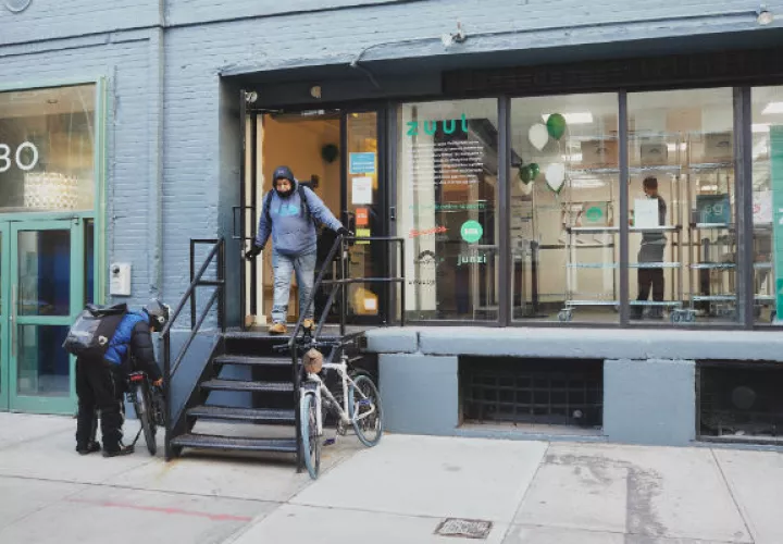 Encargados del reparto de comida entran y salen de un local en Manhattan que maneja seis restaurantes. Foto / Andrew White para The New York Times.