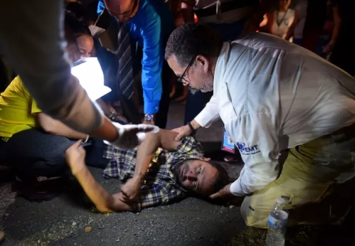 Un paramédico ayuda a un hombre después de sufrir ataques mientras él y sus vecinos permanecen afuera usando carpas de campamento y luces portátiles por temor a posibles réplicas sísmicas. FOTO/AP