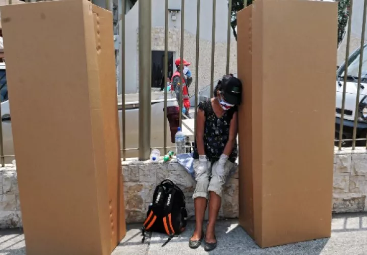 Una mujer llora afuera de un cementerio en Guayaquil junto a cajas de cartón usadas como ataúdes. Foto / Jose Sanchez/Agence France-Presse — Getty Images.