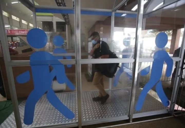 Usuarios de la terminal de transporte de Albrook pasan por una cabina de desinfección instalada en la terminal de autobuses antes de los abordajes. 