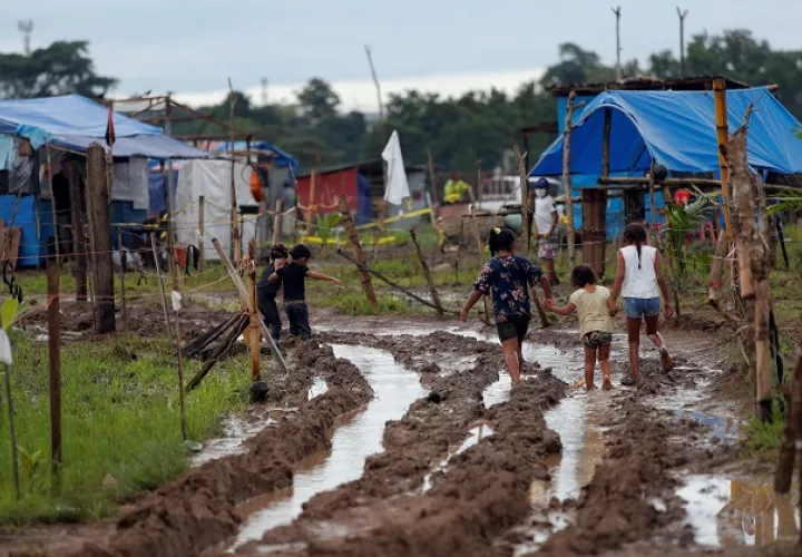 Niños recorren un camino lodoso en el terreno "Victoriano Lorenzo", en el sector de la 24 de Diciembre. Foto: EFE