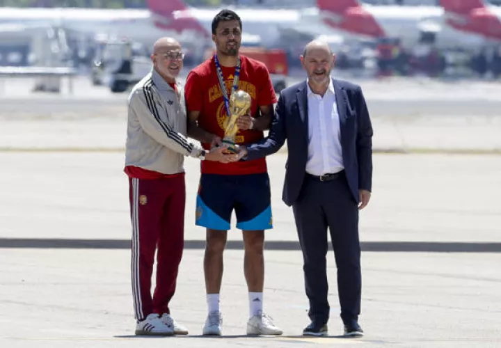El capitán de la selección española de fútbol, Rodri (cent.), que lleva el trofeo de la Copa del Mundo, acompañado del seleccionador nacional, Luis de la Fuente (i), y el presidente de la RFEF, Rafael Louzán, a su llegada al aeropuerto de Madrid Barajas. Foto: EFE