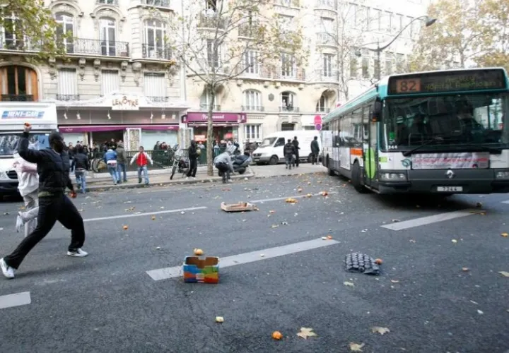 Varias personas lanzan piedras contra un autobús en París el pasado sábado en los disturbios registrados en el país. Foto: EFE