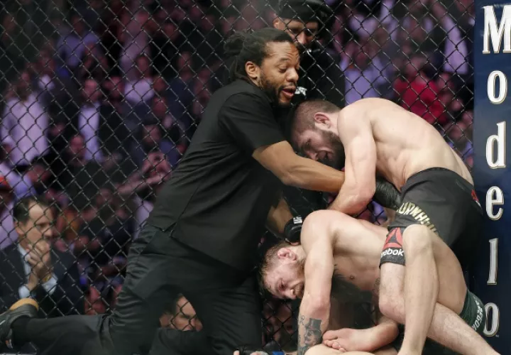 Khabib Nurmagomedov somete a  Conor McGregor (c) ante la mirada del árbitro Herb Dean (izq.). /Foto AP