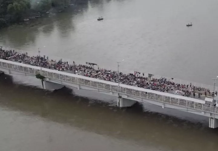 Al menos un millar de migrantes permanecen aparcados en el puente fronterizo en espera de ser atendidos. EFE
