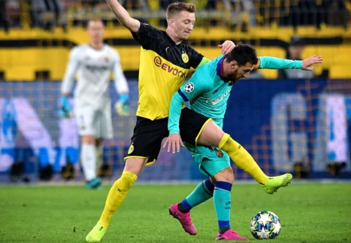 Marco Reus disputa (izq.) el balón ante Messi. AP