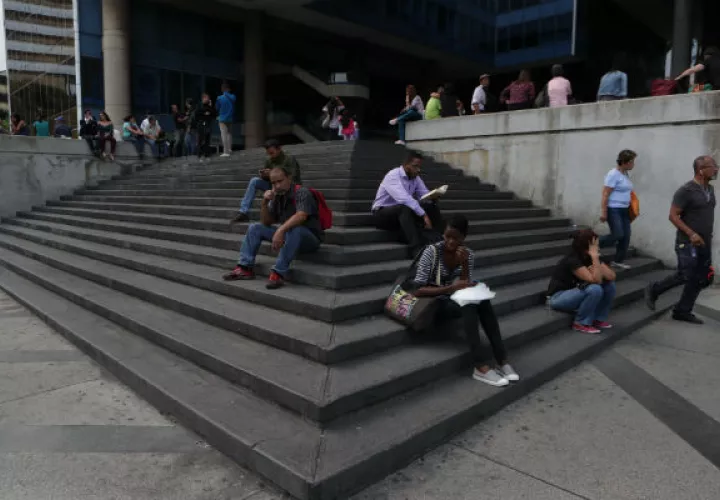  Venezolanos permanecen a la entrada de un edificio durante el apagón eléctrico en Caracas (Venezuela). Foto: EFE.