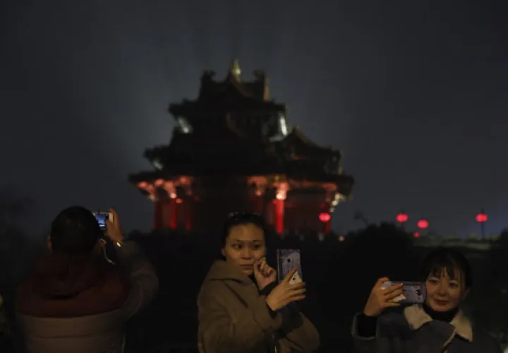  los visitantes toman fotos de la Ciudad Prohibida iluminada con luces para el Festival de los Faroles en Beijing. FOTO/AP