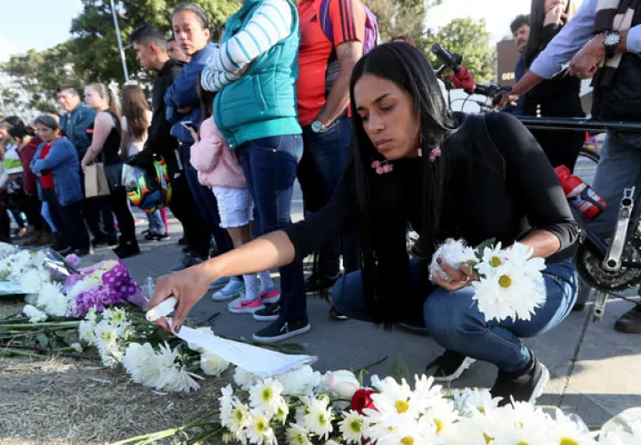 Decenas de personas llevan flores y prenden velas en honor a los policías fallecidos en el ataque de ayer en la Escuela de Cadetes de Policía General Francisco de Paula Santander, en Bogotá. FOTO/EFE