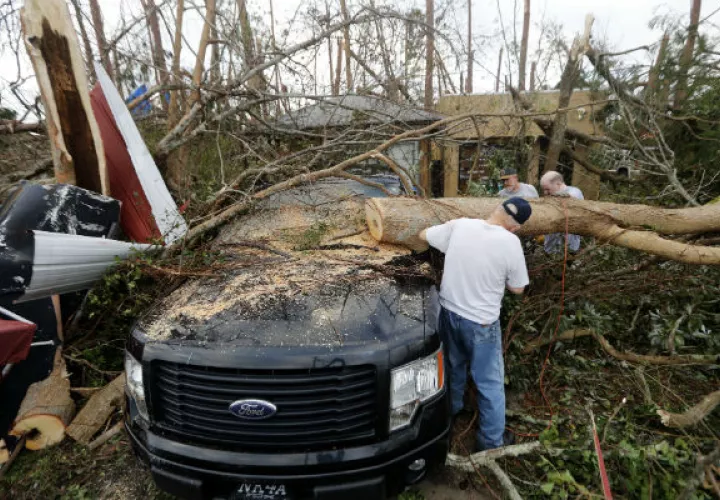 La gente corta un árbol que cae en un vehículo después del huracán Michael en la ciudad de Panamá, Florida. AP 