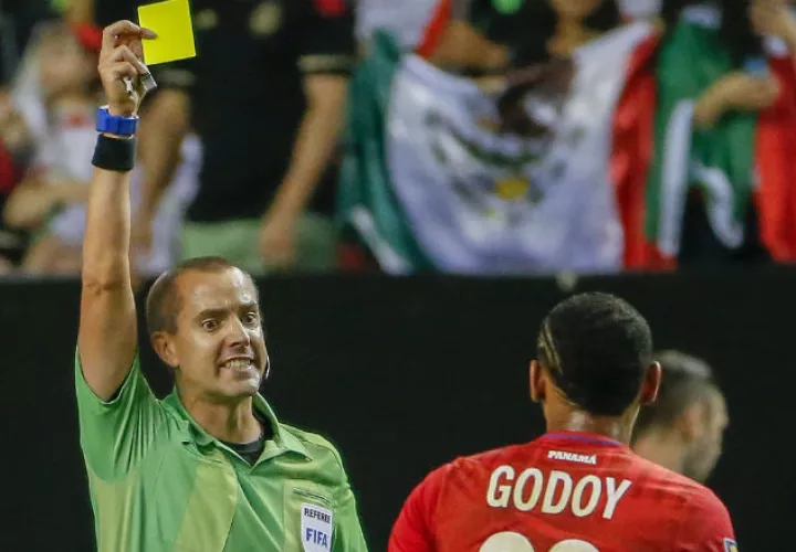 El árbitro Mark Geiger muestra tarjeta amarilla a Anibal Godoy. Foto:EFE 