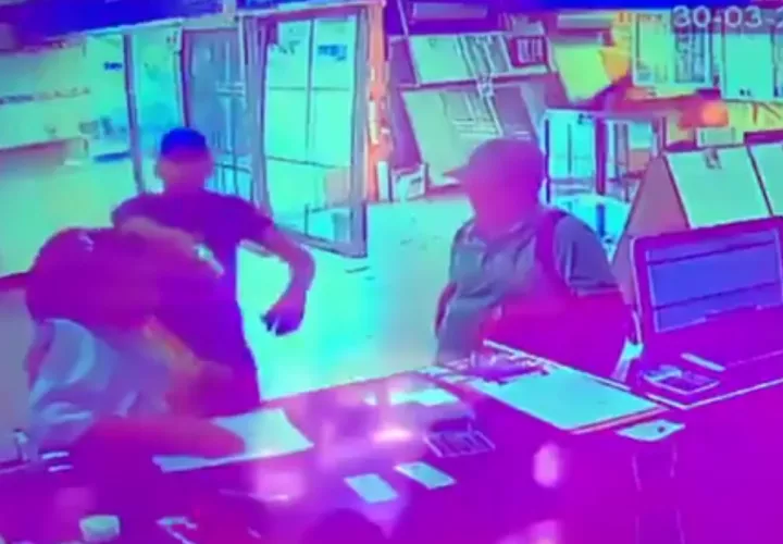Uno de los delincuentes saca un arma de fuego y apunta directamente a la persona que administraba el local comercial. 