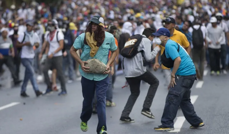 Un grupo de manifestantes huye de los gases lacrimógenos. /Foto AP