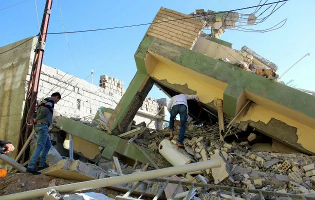 Dos hombres inspeccionan los restos de un edificio dañado. Fotos: EFE