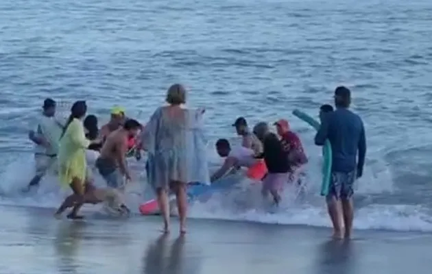 Momento en que un grupo de personas sacaba del mar a la adulta mayor. 