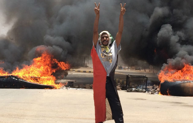 Un manifestante hace la señal de victoria ante neumáticos en llamas en Khartoum, Sudán. Foto: AP.