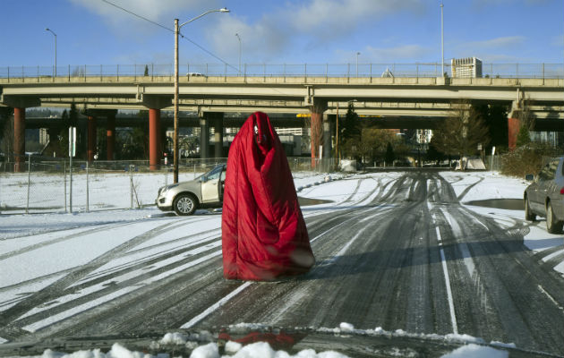 Un hombre camina por la calle cubierto con una bolsa de dormir ante el intenso frío en Portland, Oregon.  Foto: AP.