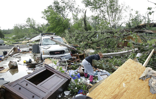 Una mujer busca pertenencias en su vivienda destrozada por un tornado. Foto: AP: 